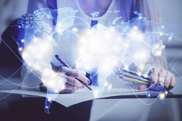 International business hologram over hands taking notes background. Concept of success. Multi exposure