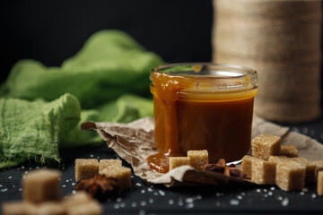 Glass jar of homemade salted caramel decorated with cane sugar and green gauze