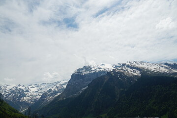 Alpine slopes partly covered with snow in springtime in Engelberg region canton Obwalden in Switzerland. The mountain range is on the background of the overcast sky.