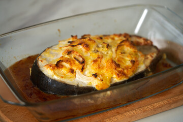 baked fish with cheese lies on a transparent dish