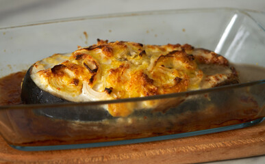 baked fish with cheese lies on a transparent dish