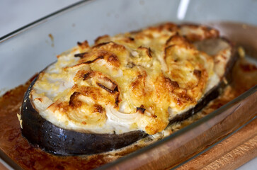 baked fish with cheese lies on a transparent dish