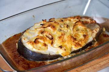 baked fish with cheese lies on a transparent dish