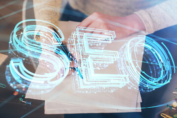 Multi exposure of woman's hands making notes with SEO icon. Concept of Search engine optimization