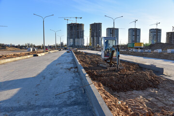 Mini excavator during road works at construction site. Screeding sand for installing borders, curbs...
