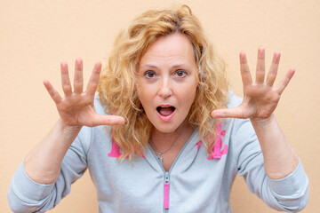 Obraz premium A white woman makes a funny expression by raising her hands close to her face