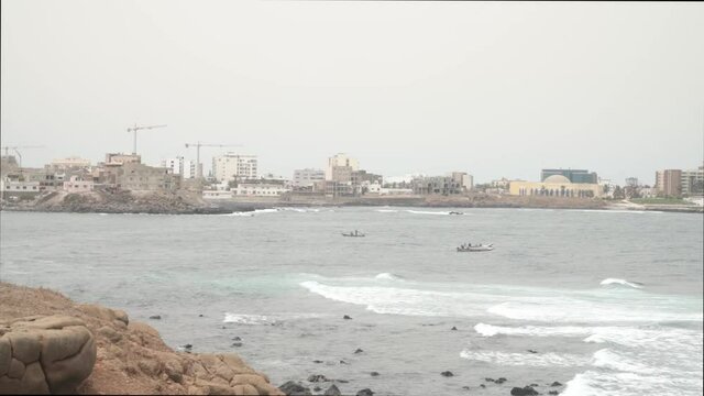 View of Dakar Senegal from Ngor island with fisherman boats passing 