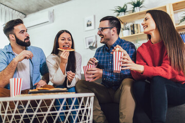 Group of young friends eating pizza in home interior.  Young people having fun together.