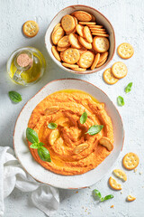 Traditional tomato hummus with crackers, oil and basil
