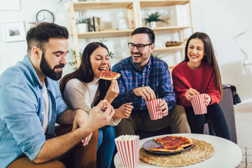 Group of young friends eating pizza in home interior.  Young people having fun together.