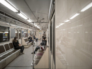 Interior of a subway train car with people in medical masks.