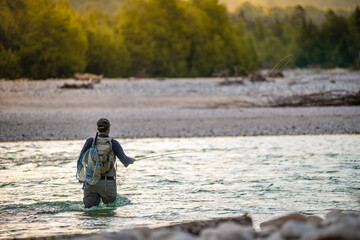Close up of a fly fisherman casts his line while wading in the middle of a river