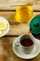 Fresh tea from the teapot is poured into a white cup.