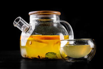 tea pot and Cup of Hot fruit tea with lemon, mint, orange on black background