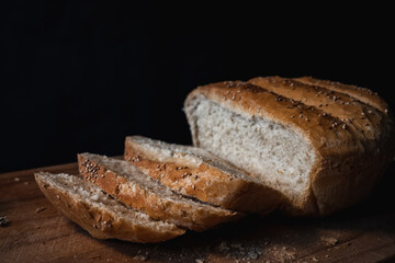 Home made and baked grain bread on a wooden table with black background