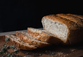Home made and baked grain bread on a wooden table with black background