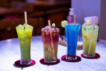Four Cold and fresh cocktail in a seaside restaurant garnished with lemon piece and ecofriendly wooden straw in Bali