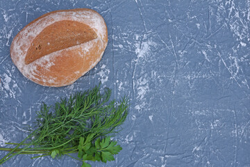 Homemade fresh bread and a bunch of dill on a gray background. View from above. Copy space