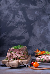 Pork and beef terrine with herbs served with tomato salad. French cuisine aspic meal