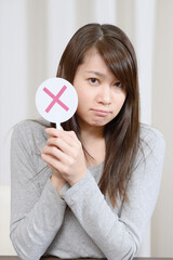 バツ印を出す若い女性