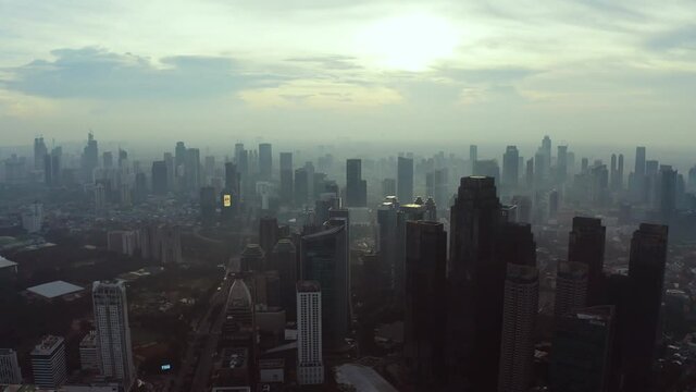 JAKARTA - Indonesia. June 04, 2020: Beautiful Jakarta cityscape at sunrise time with silhouette of skyscrapers. Shot in 4k resolution from drone flying left to right