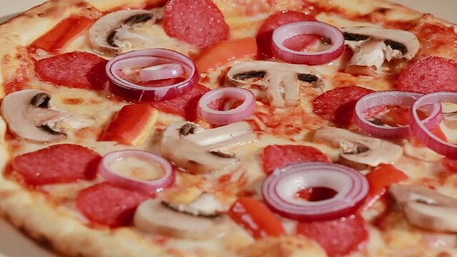 Shot of well baked pizza with melted cheese, onion, mushrooms, salami and red peper. Typical Italian pizza called capricciosa on the wooden plate. Dinner tasty snack lunch mozzarella cooking gourmet