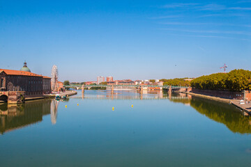 Toulouse landmarks on the bank of river Garone. Hospital de La Grave and Ferries Wheel reflected in Garone river.
