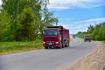 Fototapeta na wymiar Tipper Dump Truck transported sand from the quarry on driving along highway. Modern Heavy Duty Dump Truck with unloads goods by itself through hydraulic or mechanical lifting