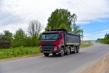 Fototapeta na wymiar Tipper Dump Truck transported sand from the quarry on driving along highway. Modern Heavy Duty Dump Truck with unloads goods by itself through hydraulic or mechanical lifting