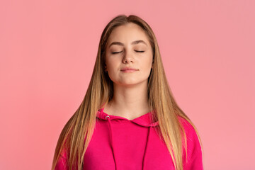 Fototapeta premium Teenager girl with closed eyes enjoy the moment, isolated on pink background