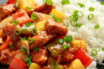 Pineapple and Chicken in sweet and sour sauce with bell pepper, rice and spring onion in black plate