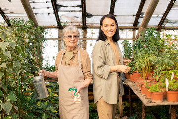 Portrait of smiling senior and young multi-ethnic women standing at plants in greenhouse