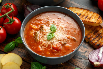 Seasonal vegetables classic minestrone soup with pasta served with cheese, grilled sour dough bread and basil leaves