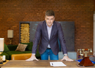 Portrait of a middle-aged businessman leaning on his desk