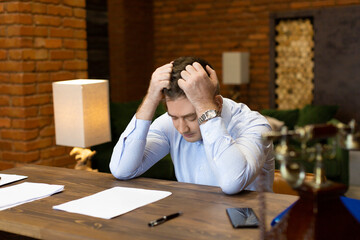 Obraz premium Critical error in documents. Portrait of a businessman at the table clutching his head.