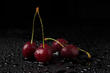 Macro photo of group red cherry with water drops on black background.