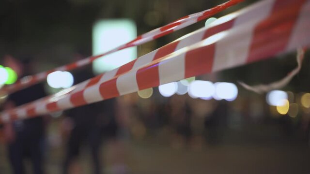 Police red & white stripes tape crime scene or demonstration, cops in background