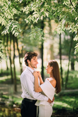 Bride Adjusting Groom's Necktie Standing And Hugging In Park