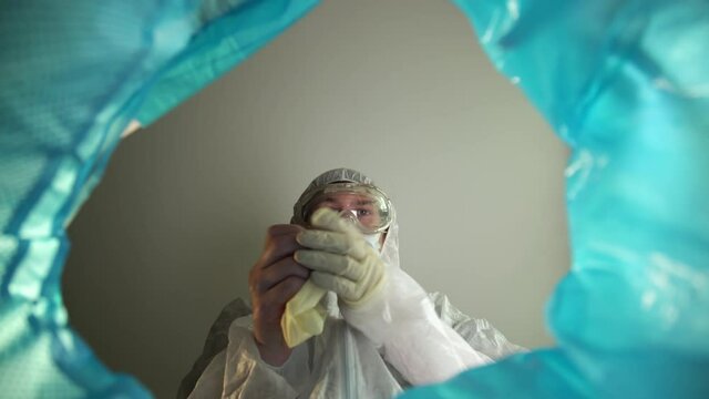End of quarantine victory over the coronavirus. View from the trash can a man doctor removes a medical mask and latex gloves and throws them. Trash can with disposable personal protective equipment
