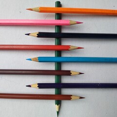 colored pencils on wooden background placed one on one