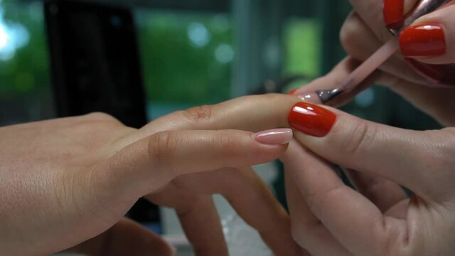 manicure service. Manicurist paints nails  with red gel polish. Nail polish application. Manicured red nails.