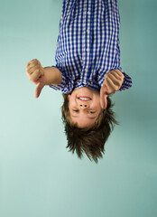 Happy boy hanging upside down, holding his hands in front of him