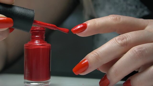 manicure service. Manicurist paints nails  with red gel polish. Nail polish application. Manicured red nails.