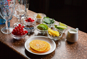 Various fruits and berries prepared for making cocktails lie in saucers on a bar counter