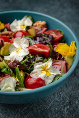 Diet vegetarian salad of cherry tomatoes, avocado, mix of greens with flowers.