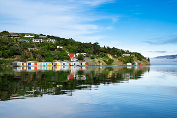 Fototapeta na wymiar Colorful Boat Sheds with beautiful reflection on daytime at Duvauchelle, Akaroa Harbour on Banks Peninsula in South Island, New Zealand.
