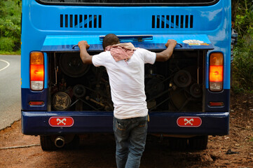 African man repairs his bus engine/motor after a car breakdown in the middle of the african rain...