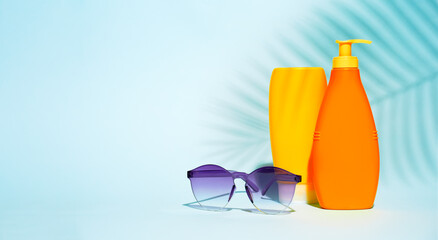 Orange containers without label for lotion, purple glasses on blue background