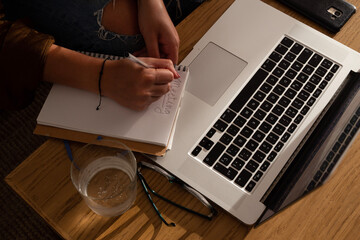 home work space - work from home concept - girl writing notes with a laptop sitting on a sofa by a wooden desk