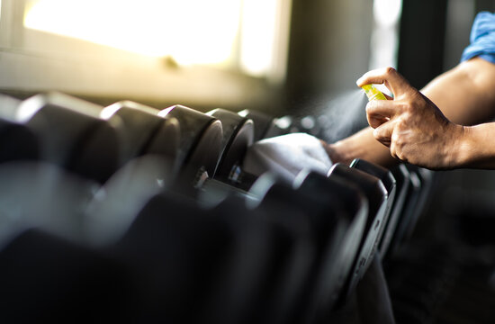 Fitness Staff Cleaning Exercise Machines Alcohol Sanitizer Spray At The Gym. Preventive Disease Of The Covid 19 Virus